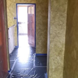 Oleksandr Misiiuk - Korytarz w trakcie malowania ścian na odcienie beżu, podłoga zabezpieczona folią, framugi oklejone taśmą malarską.