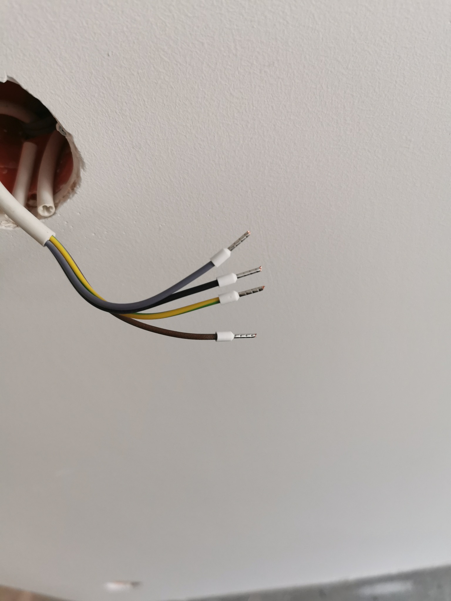 Wystające z otworu w suficie przewody elektryczne z końcówkami tulejkowymi, gotowe do podłączenia.