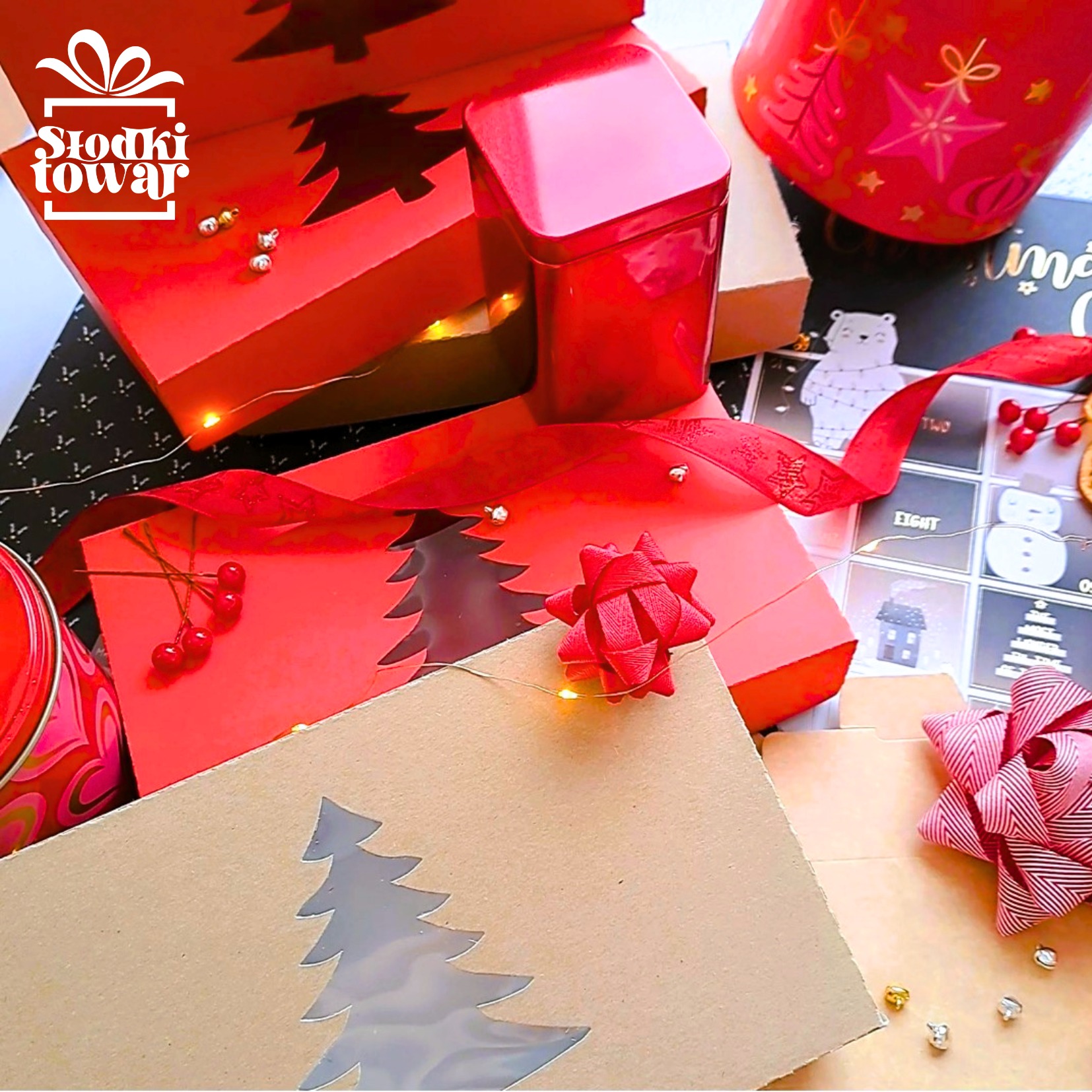Zestaw świątecznych pudełek i puszek w czerwonych i brązowych odcieniach, ozdobionych wyciętymi motywami choinek i wstążkami, oświetlony delikatnymi lampkami.