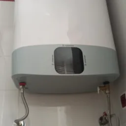 Zamontowany elektryczny podgrzewacz wody Ariston w łazience w Gliwicach, widoczne białe płytki z motywem kwiatowym i podłączenia hydrauliczne.