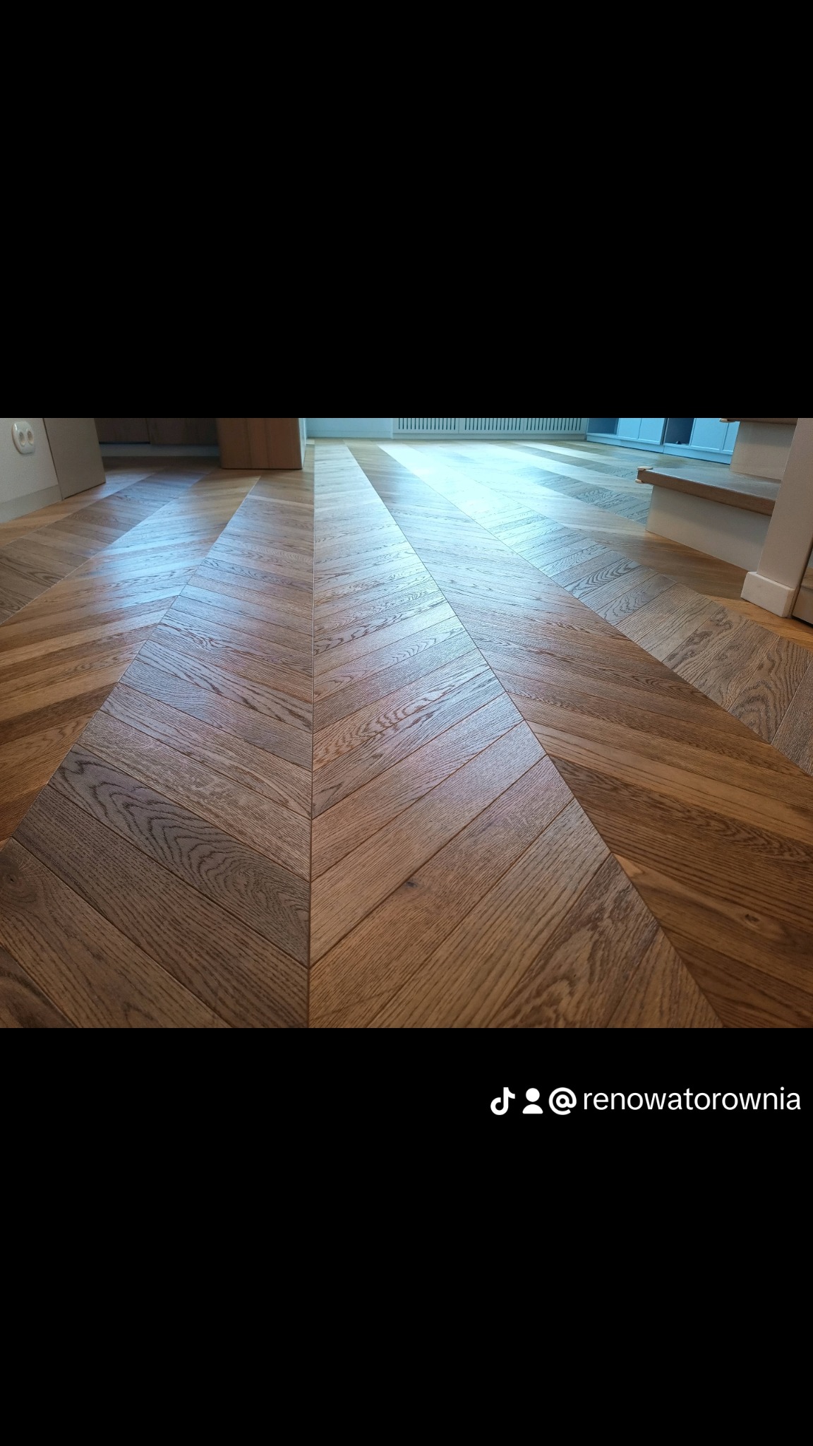 Parkiet ułożony we wzór jodełki francuskiej, po renowacji, widoczne schody w tle.