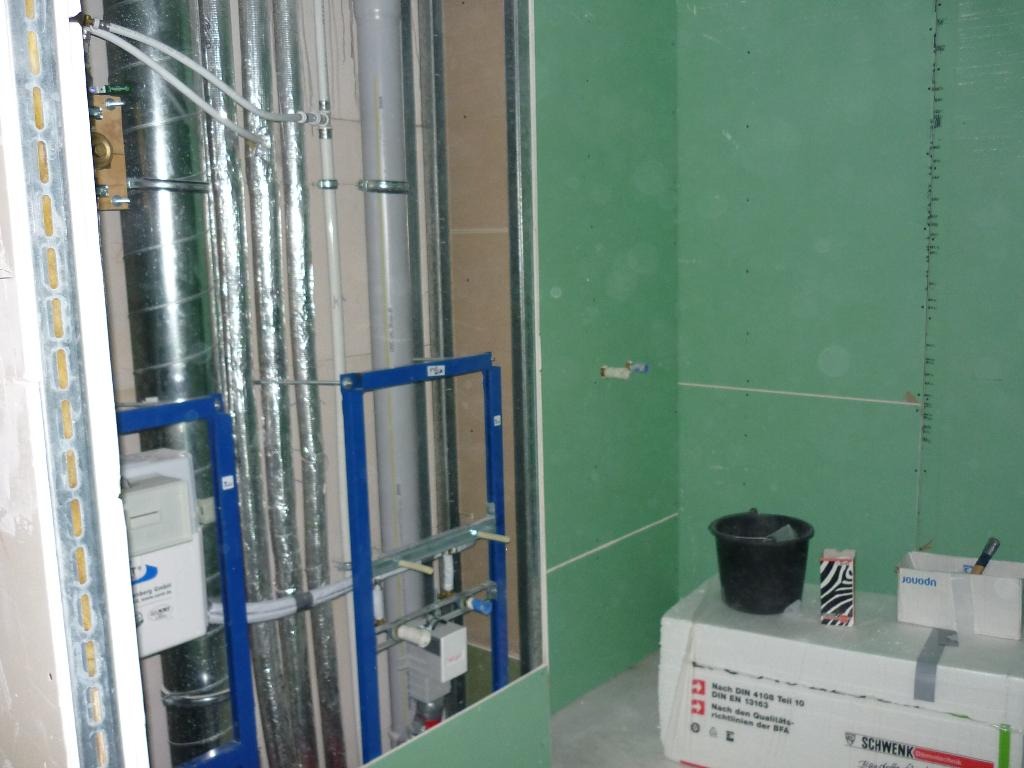 Instalacja wodno-kanalizacyjna w trakcie montażu w łazience, widoczne rury, stelaż podtynkowy i płyty karton gips na ścianie.