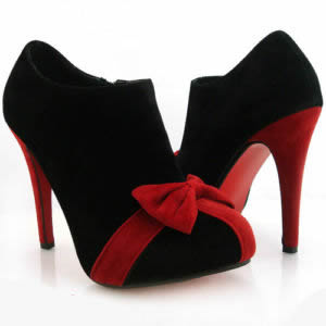 Eleganckie czarno-czerwone botki na wysokim obcasie, zamszowe, ozdobione czerwoną kokardą, ustawione na białym tle.