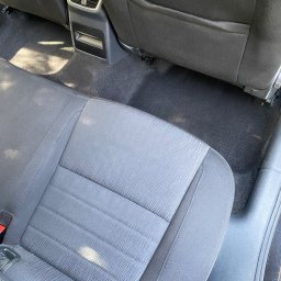 Brak - Wnętrze samochodu przed czyszczeniem: plamy widoczne na tylnej kanapie i dywanikach pod siedzeniami.