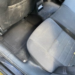 Brak - Wnętrze samochodu z widocznymi, mocno zabrudzonymi tylnymi siedzeniami, podłogą i elementami tapicerki przed czyszczeniem.