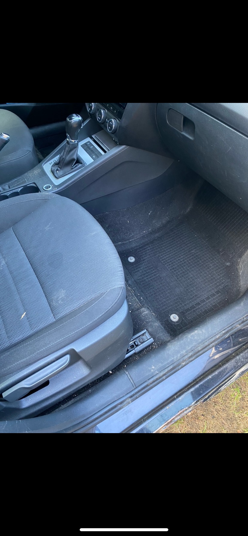 Wnętrze brudnego samochodu z widocznymi plamami i kurzem na siedzeniach, dywanikach i konsoli środkowej.