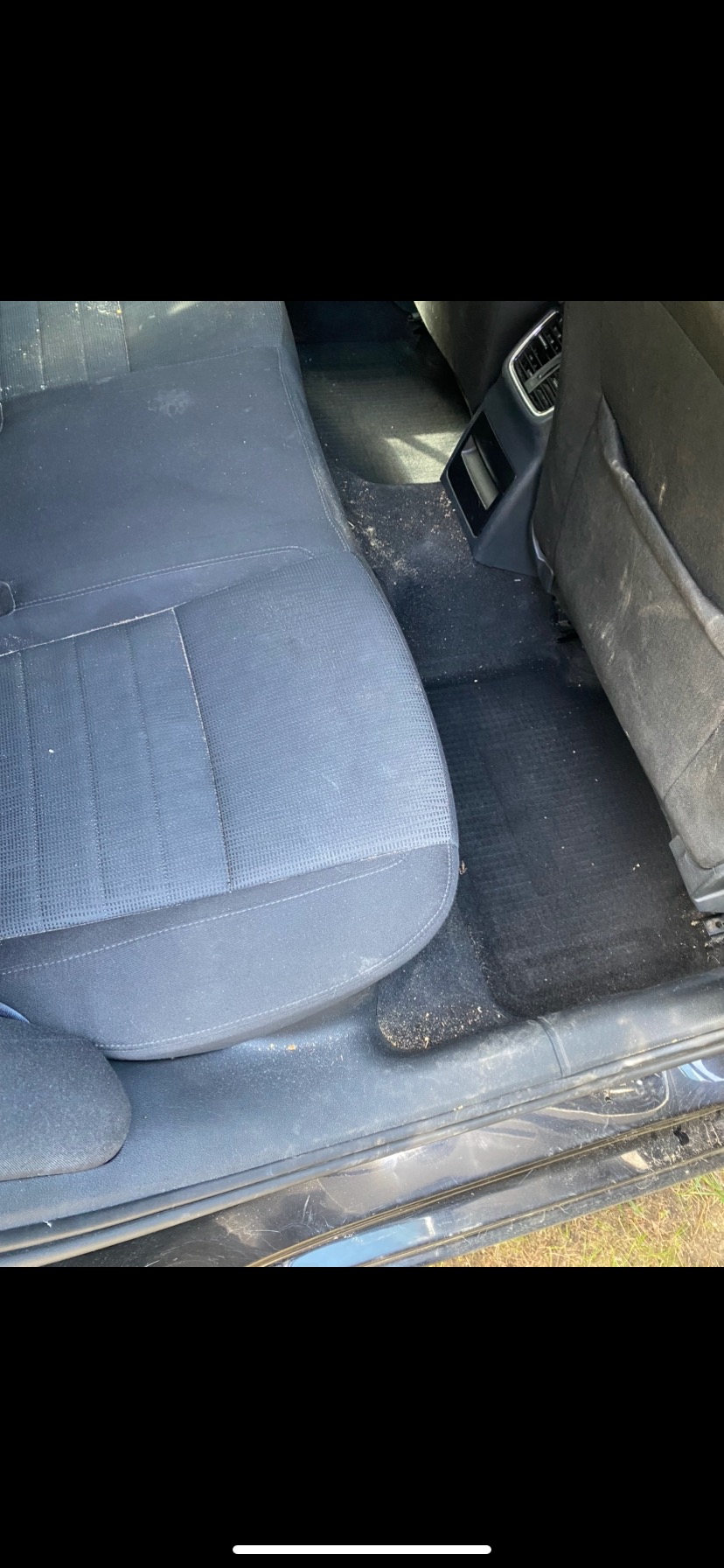 Wnętrze samochodu z widocznymi zabrudzeniami na tylnych siedzeniach, podłodze i progach, wymagające czyszczenia.