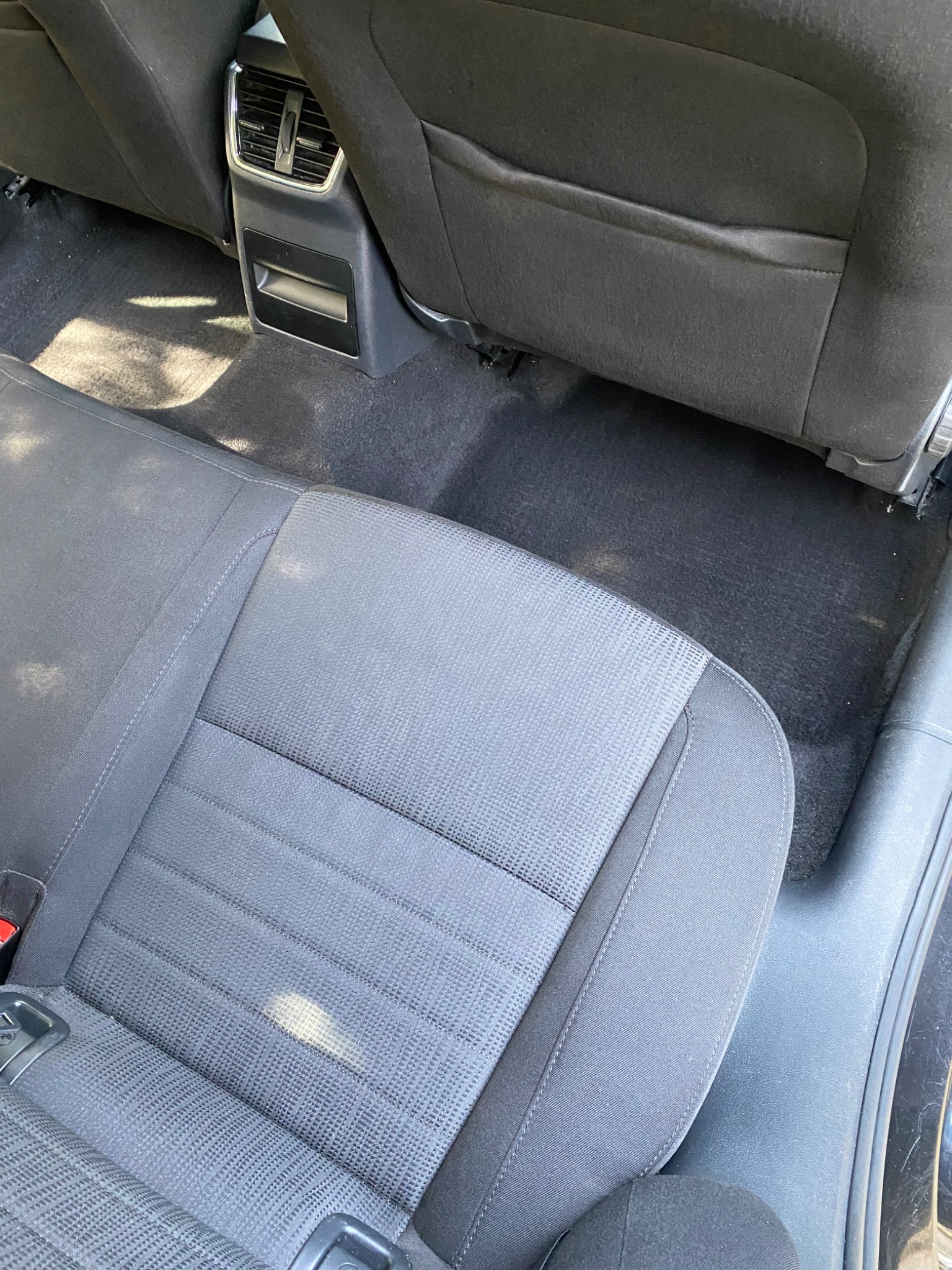 Wnętrze samochodu przed czyszczeniem: plamy widoczne na tylnej kanapie i dywanikach pod siedzeniami.