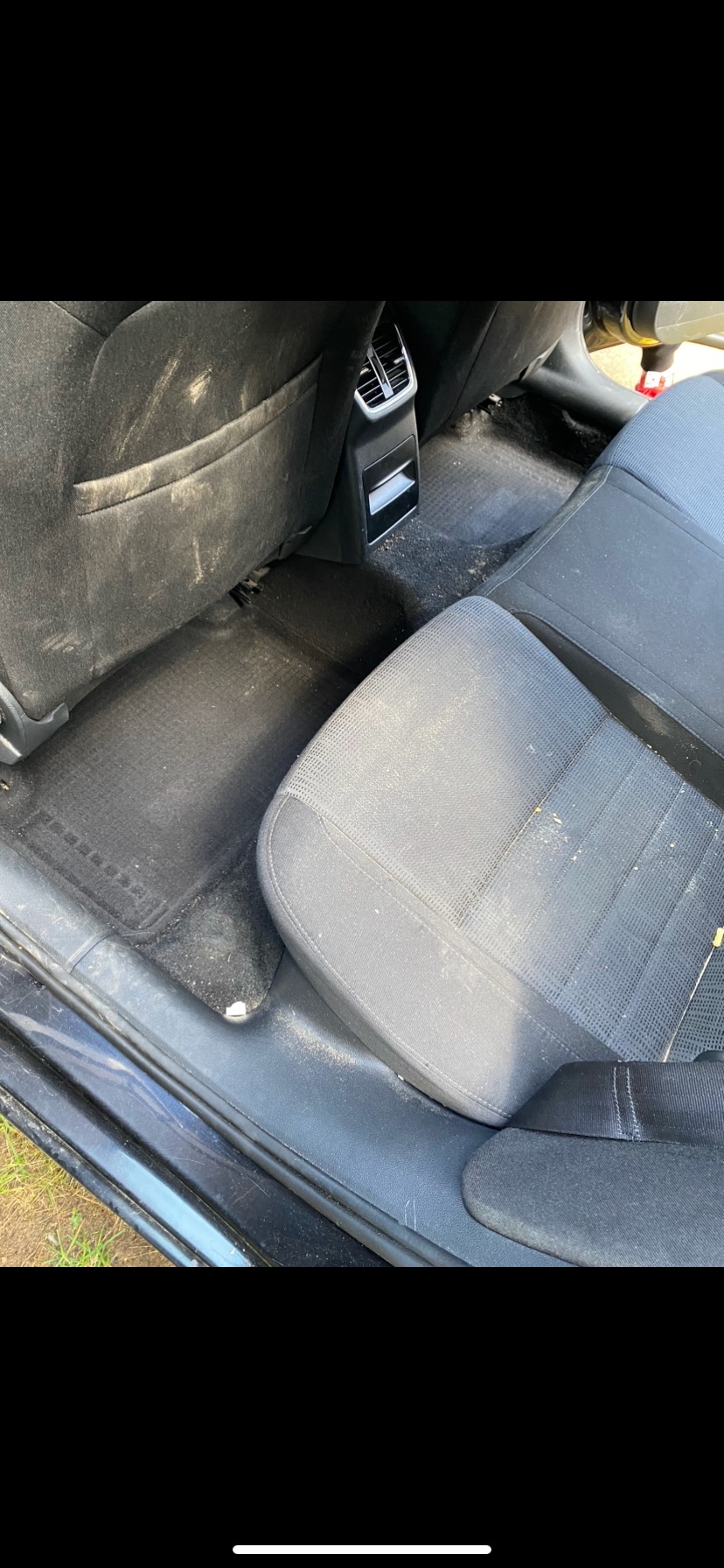Wnętrze samochodu z widocznymi, mocno zabrudzonymi tylnymi siedzeniami, podłogą i elementami tapicerki przed czyszczeniem.