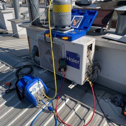 Inżynieria Ciepła Sebastian Kazior - Sprzęt do serwisu klimatyzacji Haier na dachu budynku, widoczna butla z czynnikiem chłodniczym, pompa próżniowa VALUE, manometry i narzędzia.