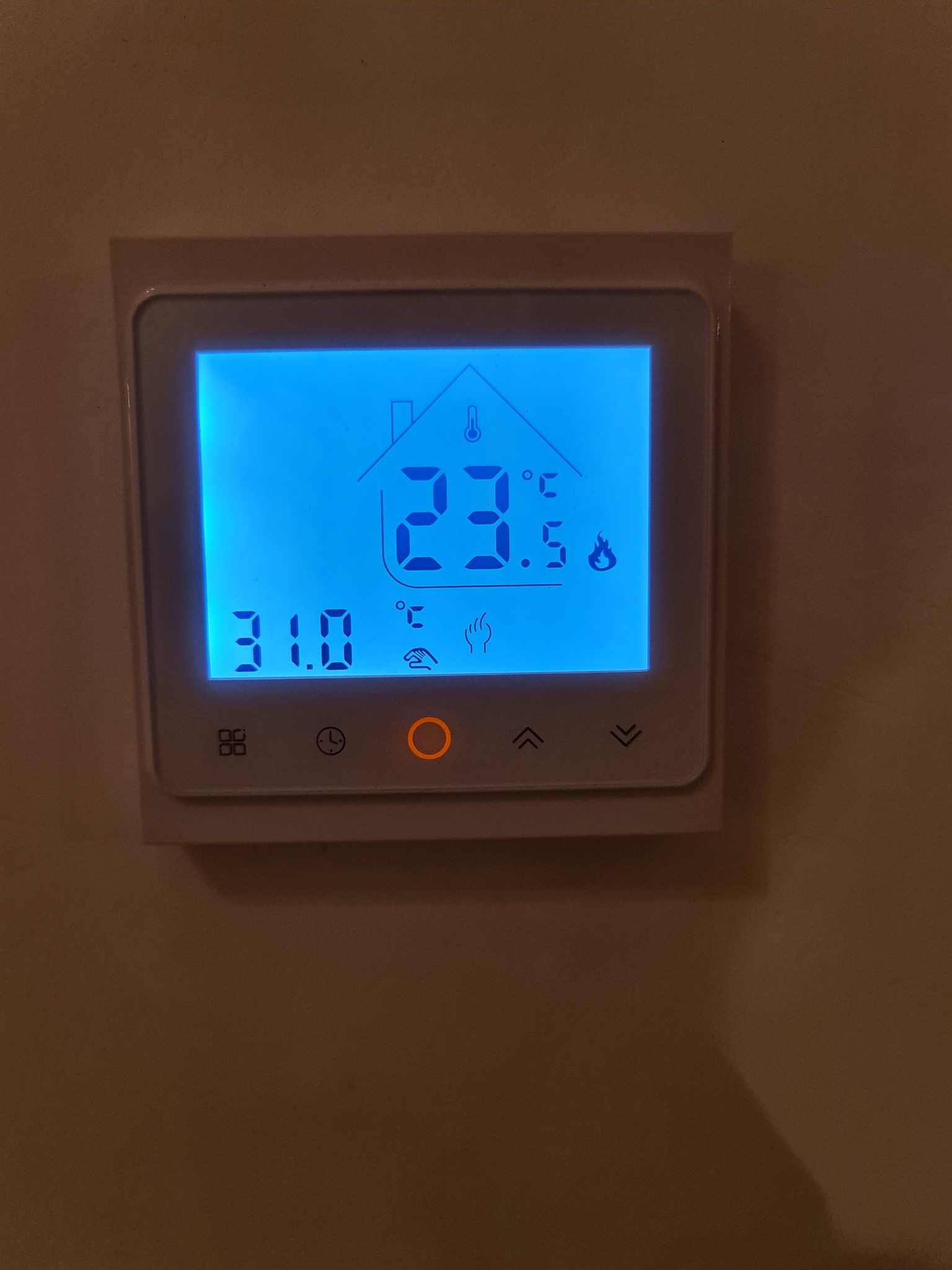 Biały, kwadratowy termostat ścienny z niebieskim wyświetlaczem LCD pokazującym temperaturę 23.5°C i 31.0°C, ustawienia ogrzewania podłogowego, czasu i intensywności grzania.
