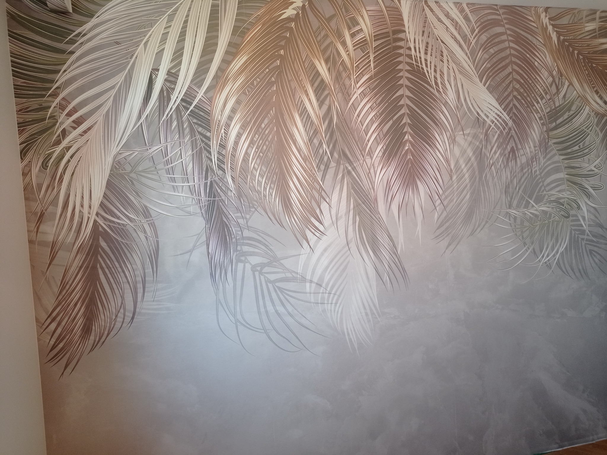 Dekoracyjna ściana z motywem liści palm w odcieniach szarości i złota, wykonana w Grójcu. Efektowna tekstura i subtelne przejścia kolorystyczne.