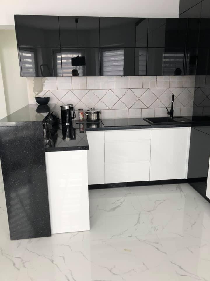Nowoczesna kuchnia z czarnymi, lakierowanymi szafkami górnymi, białymi szafkami dolnymi i czarnym blatem z efektem brokatu, wykończona płytkami w romby i marmurową podłogą.