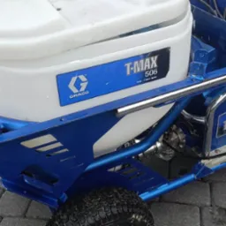 Agregat malarski Graco T-MAX 506 na kostce brukowej, widoczne detale konstrukcji w kolorze niebieskim.