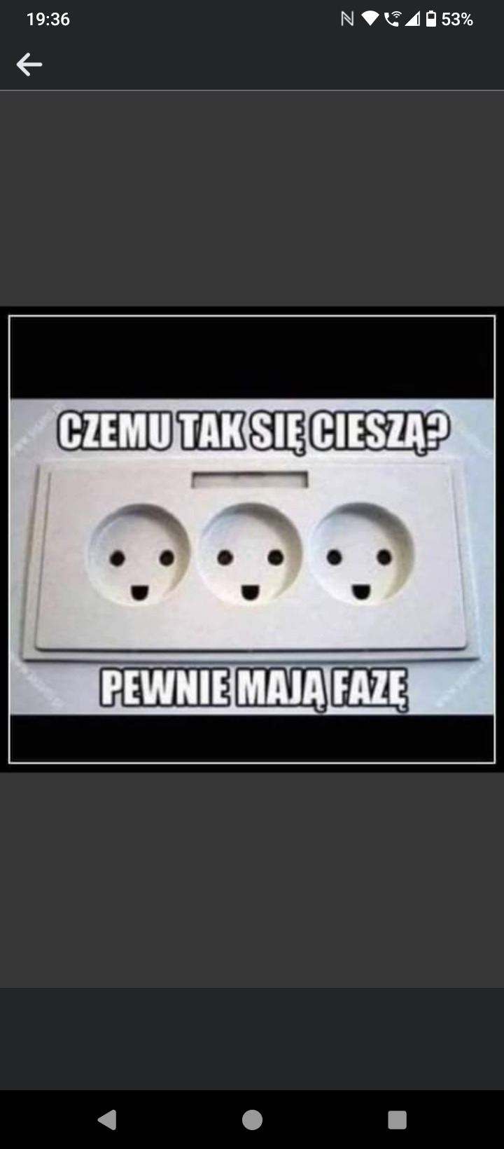 Białe gniazdko elektryczne potrójne z narysowanymi uśmiechniętymi buziami, nad nim napis 'Czemu tak się cieszą?', a pod nim 'Pewnie mają fazę'.