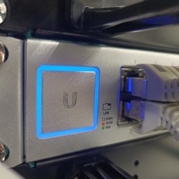 CONSOLID SP. Z O.O. - Szczegółowe ujęcie portu sieciowego z podłączonymi kablami Ethernet, diody sygnalizujące status połączenia, obudowa urządzenia z logo podświetlonym na niebiesko.