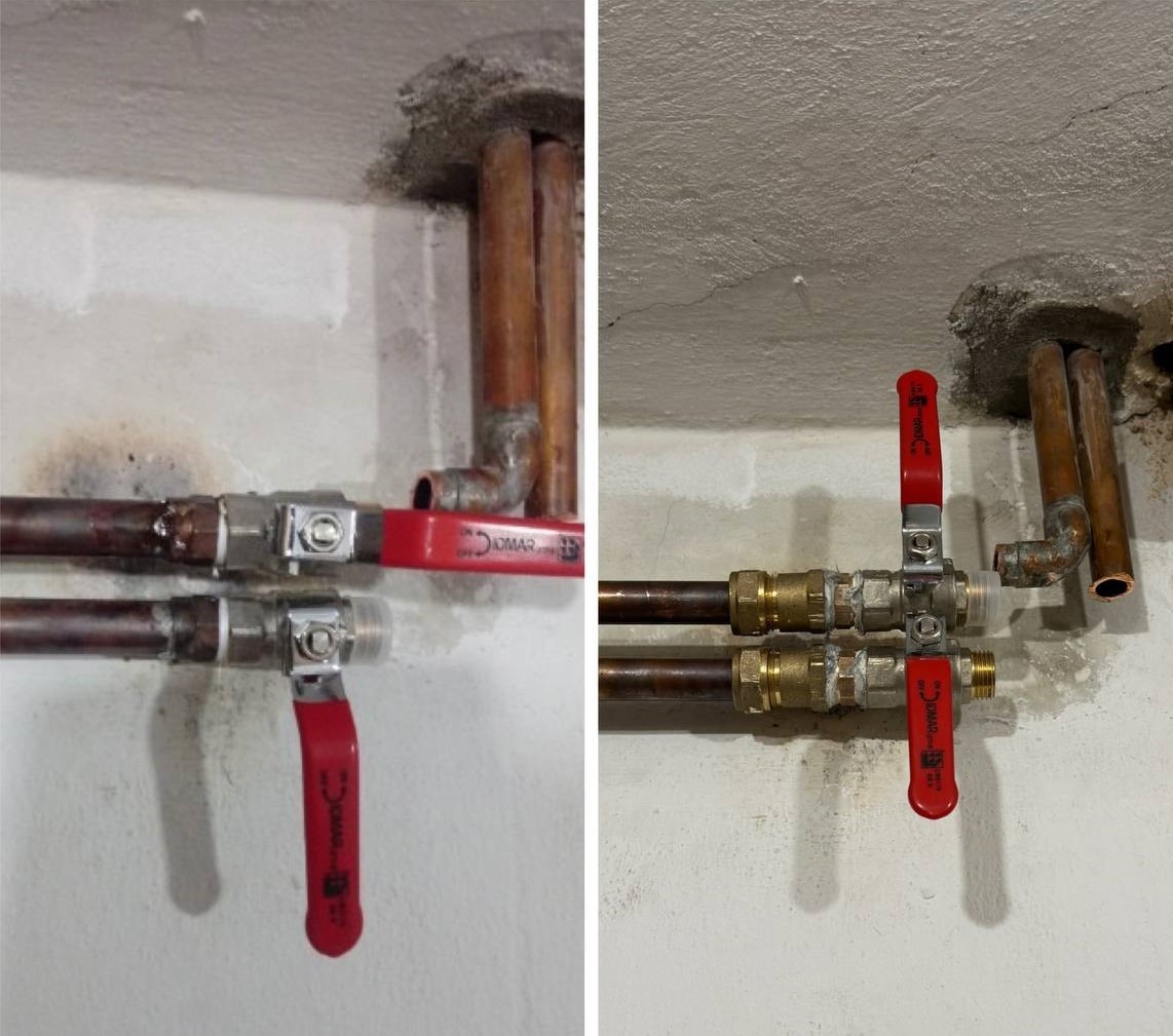 Miedziane rury instalacji wodnej z zaworami kulowymi o czerwonych uchwytach, zamontowane przy suficie z widocznymi śladami po kuciu.