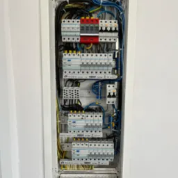 Otwarta skrzynka rozdzielcza z zainstalowanymi bezpiecznikami i okablowaniem w mieszkaniu we Wrocławiu, widok z bliska.