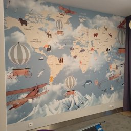 RW Remonty i Wykończenia - Tapeta na ścianie pokoju dziecięcego z motywem mapy świata, ozdobiona rysunkami zwierząt, samolotów i balonów, widoczne gniazdka elektryczne na ścianie.