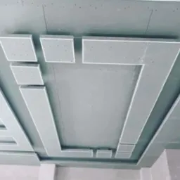 Sufit z płyt kartonowo-gipsowych, dekoracyjna konstrukcja z prostokątnych elementów i listew, widoczne ślady po szpachlowaniu, surowy stan wykończenia.