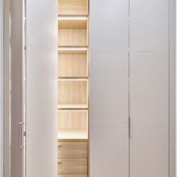 PKN Estate Sp. z o.o. - Biała szafa wnękowa z oświetleniem LED, drewniane półki i szuflady. Częściowo otwarte drzwi ukazują wnętrze. Minimalistyczny design.