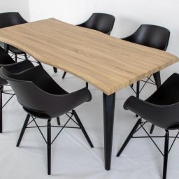 PKN Estate Sp. z o.o. - Stół z blatem drewnianym o nieregularnych krawędziach i sześcioma czarnymi krzesłami na metalowych nogach. Ustawienie na białym tle, podkreślające nowoczesny design.