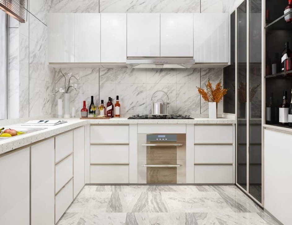 Nowoczesna kuchnia z białymi, lakierowanymi frontami szafek, marmurowym blatem i ścianą. Na blacie butelki i dekoracje. Widoczny piekarnik i przeszklona witryna.