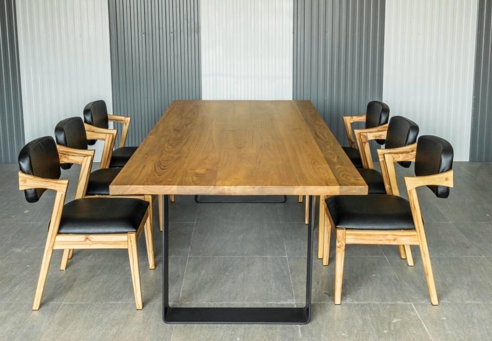 Długi, drewniany stół z czarnymi metalowymi nogami otoczony ośmioma krzesłami z jasnego drewna i czarnymi skórzanymi siedziskami na szarym tle.