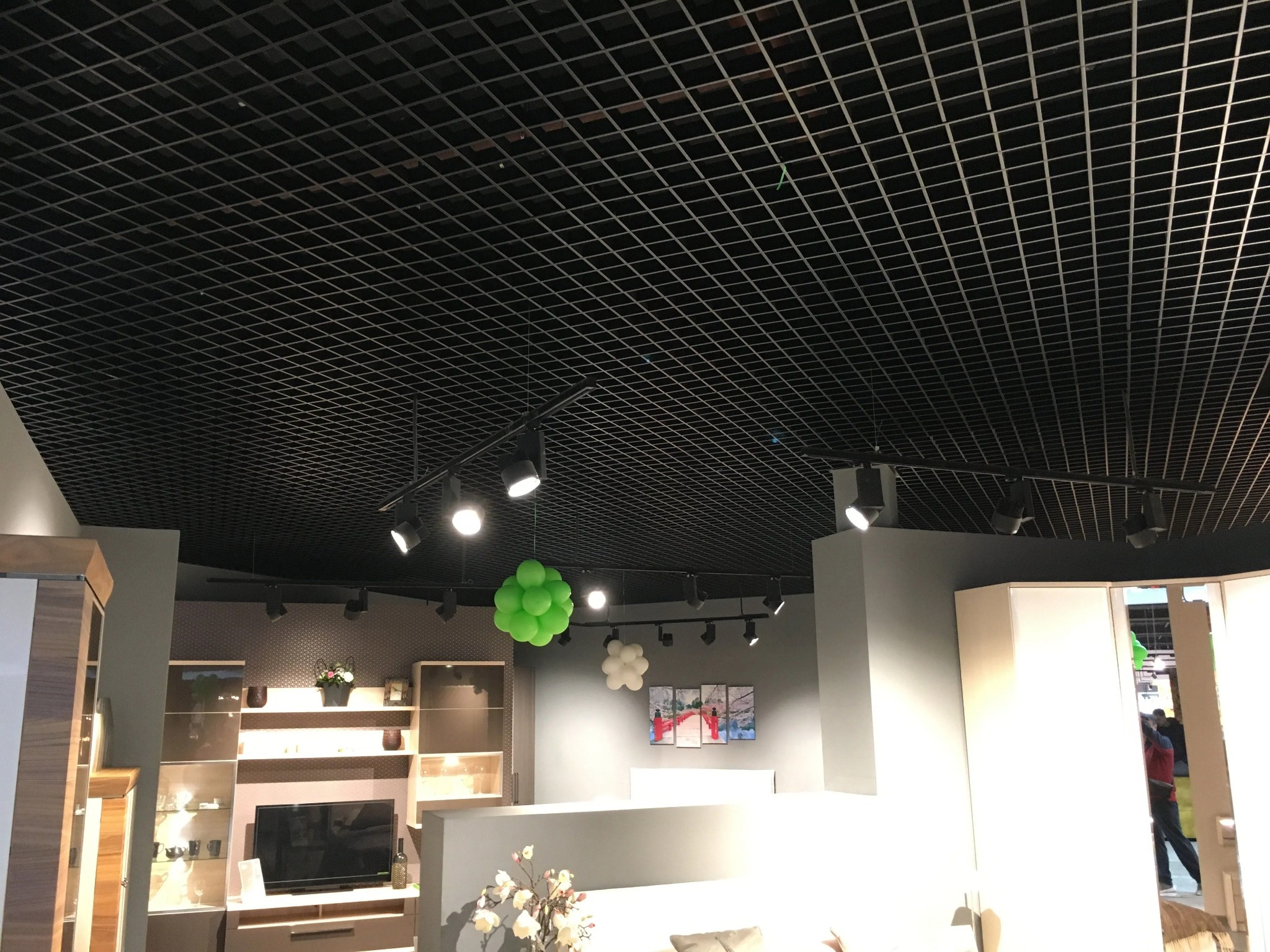Czarny sufit rastrowy z oświetleniem punktowym w nowoczesnym wnętrzu, widoczne dekoracje z balonów i meble.