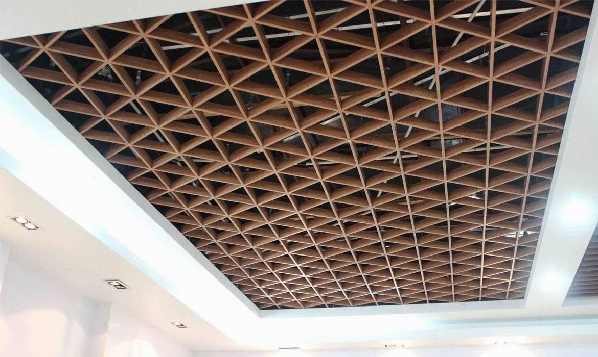 Drewniana konstrukcja sufitowa z trójkątnymi elementami, widok z dołu, oświetlenie punktowe w białym suficie podwieszanym.