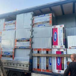 e-oknadrzwi.pl Materiały Budowlane Online - Załadunek materiałów izolacyjnych marki Arsanit Thermo Fasada Lambda na samochód ciężarowy, widoczni dwaj mężczyźni przy pracy, jeden wchodzi po drabinie, drugi nadzoruje załadunek.