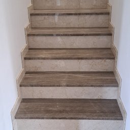 B.U. REM-BUD BOGUSŁAW BUCZKO - Beżowe schody z kamienia naturalnego z ciemniejszymi wstawkami, widok z dołu na górę, białe ściany po bokach.