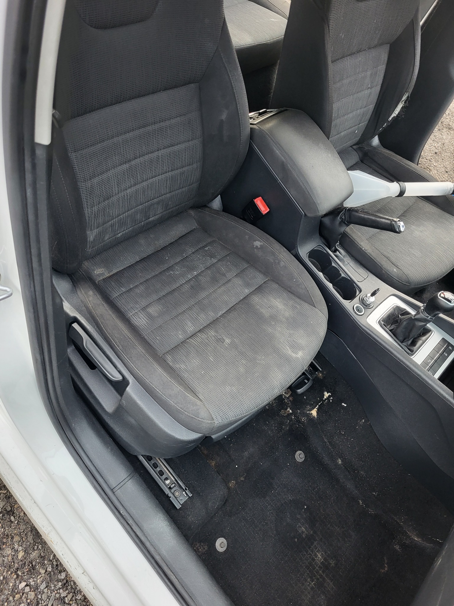 Wnętrze samochodu z bardzo zabrudzonymi tapicerowanymi siedzeniami i podłogą, widoczne ślady użytkowania i zaniedbania.