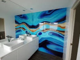 Szklana ściana w łazience z abstrakcyjnym wzorem w odcieniach błękitu, brązu i bieli, zamontowana nad umywalką nablatową.