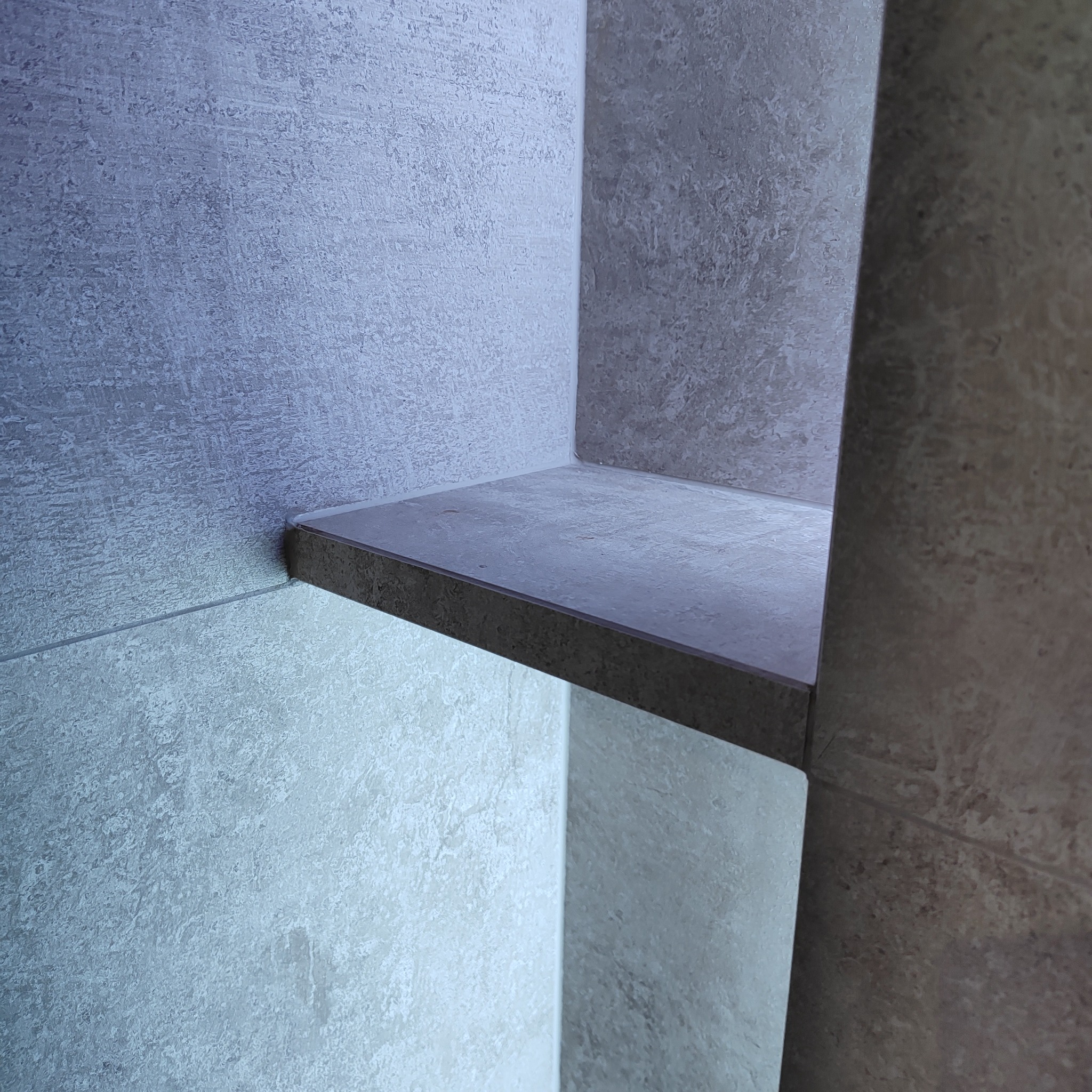 Półka z płytek ceramicznych w rogu pomieszczenia, imitacja kamienia, podświetlenie LED od dołu.