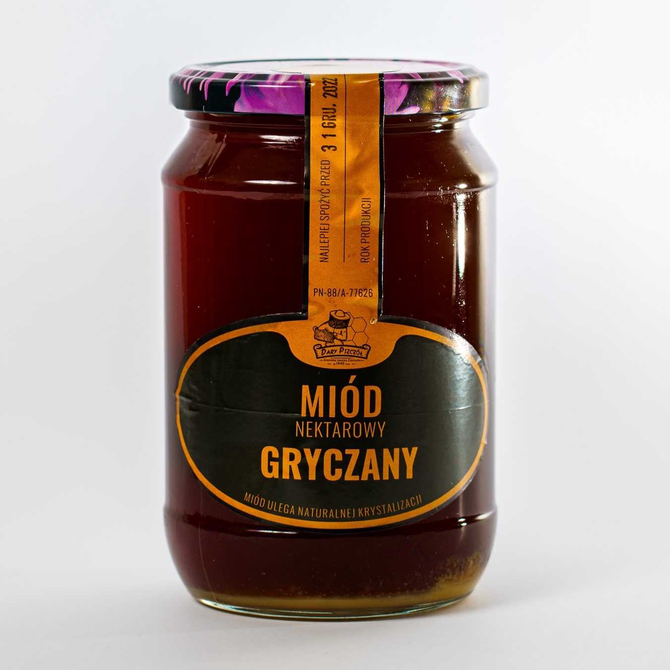 Słoik miodu gryczanego z etykietą 'Dary Pszczół', z widoczną datą ważności do 31 grudnia 2022 roku i delikatną krystalizacją na dnie słoika.