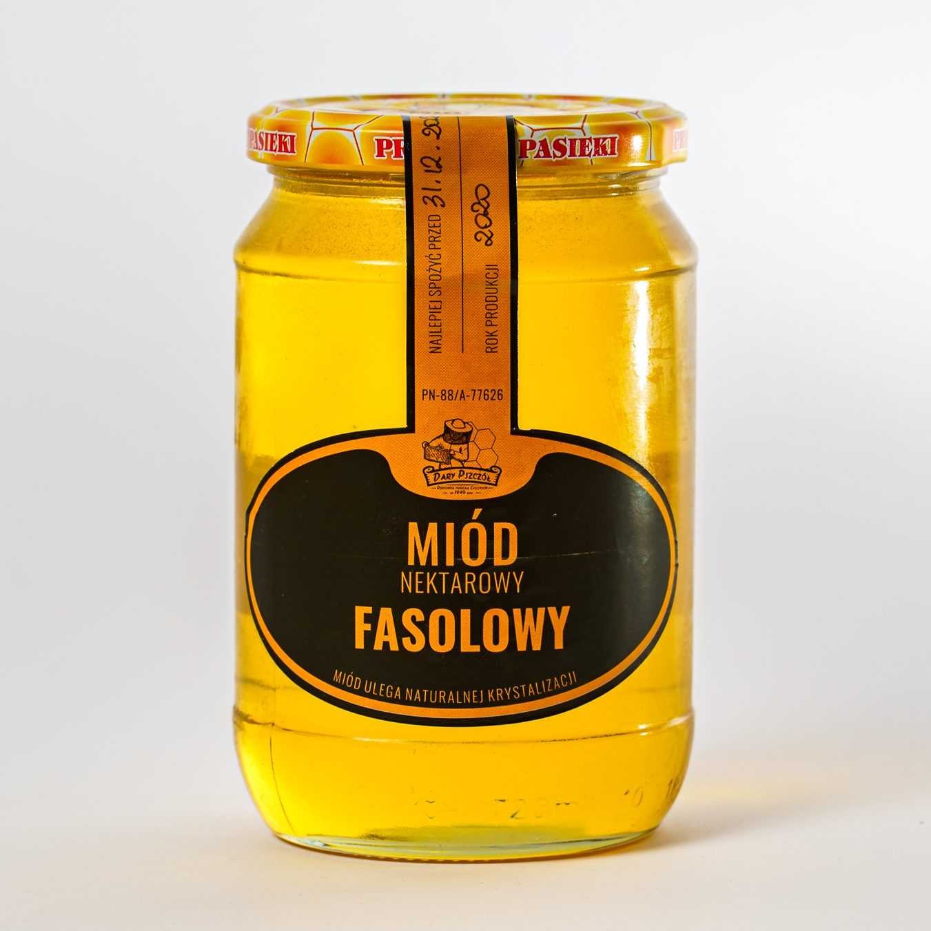 Słoik nektarowego miodu fasolowego na białym tle, z widoczną etykietą informującą o dacie ważności do 31.12.2020 i roku produkcji 2020.