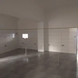 Wnętrze łazienki w trakcie remontu: ułożone szare płytki podłogowe, białe płytki ścienne do wysokości sufitu z wyprowadzonymi instalacjami wodno-kanalizacyjnymi, widoczne przewody elektryczne...