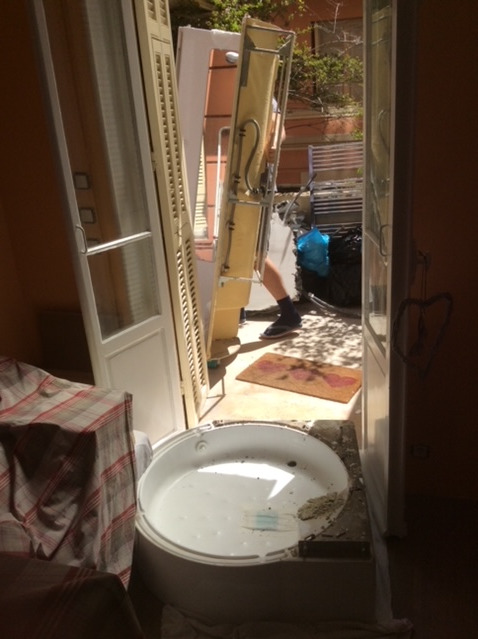 Demontaż okien balkonowych i wanny podczas remontu, widoczny fragment podłogi i wyposażenia wnętrza.