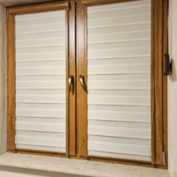 Zamknięte dwuskrzydłowe okno z drewnianą ramą i kremowymi poziomymi przesłonami w stylu dzień i noc, widoczny fragment grzejnika pod parapetem.