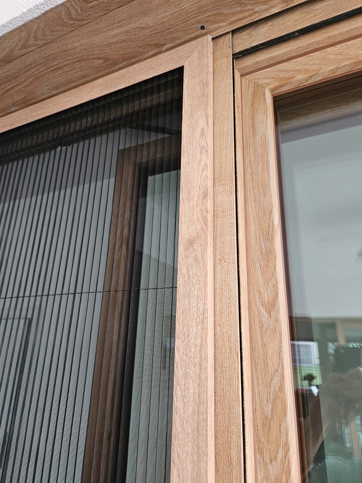 Złożona, plisowana siatka okienna w drewnianej ramie, widoczna faktura drewna, zbliżenie na detale konstrukcyjne.