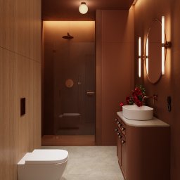 Jacek Gonera - Studio Projektowania Architektury Wnętrz - Nowoczesna łazienka w odcieniach brązu z kabiną prysznicową typu walk-in, umywalką nablatową i okrągłym lustrem z oświetleniem LED. Całość dopełniają kwiaty w wazonie.