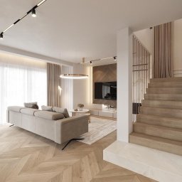 Wawrzyniak Karol - Jasne wnętrze salonu z drewnianą podłogą w jodełkę, beżową sofą, schodami z drewnianymi stopniami i ścianą z telewizorem, oświetlone nowoczesnymi lampami.