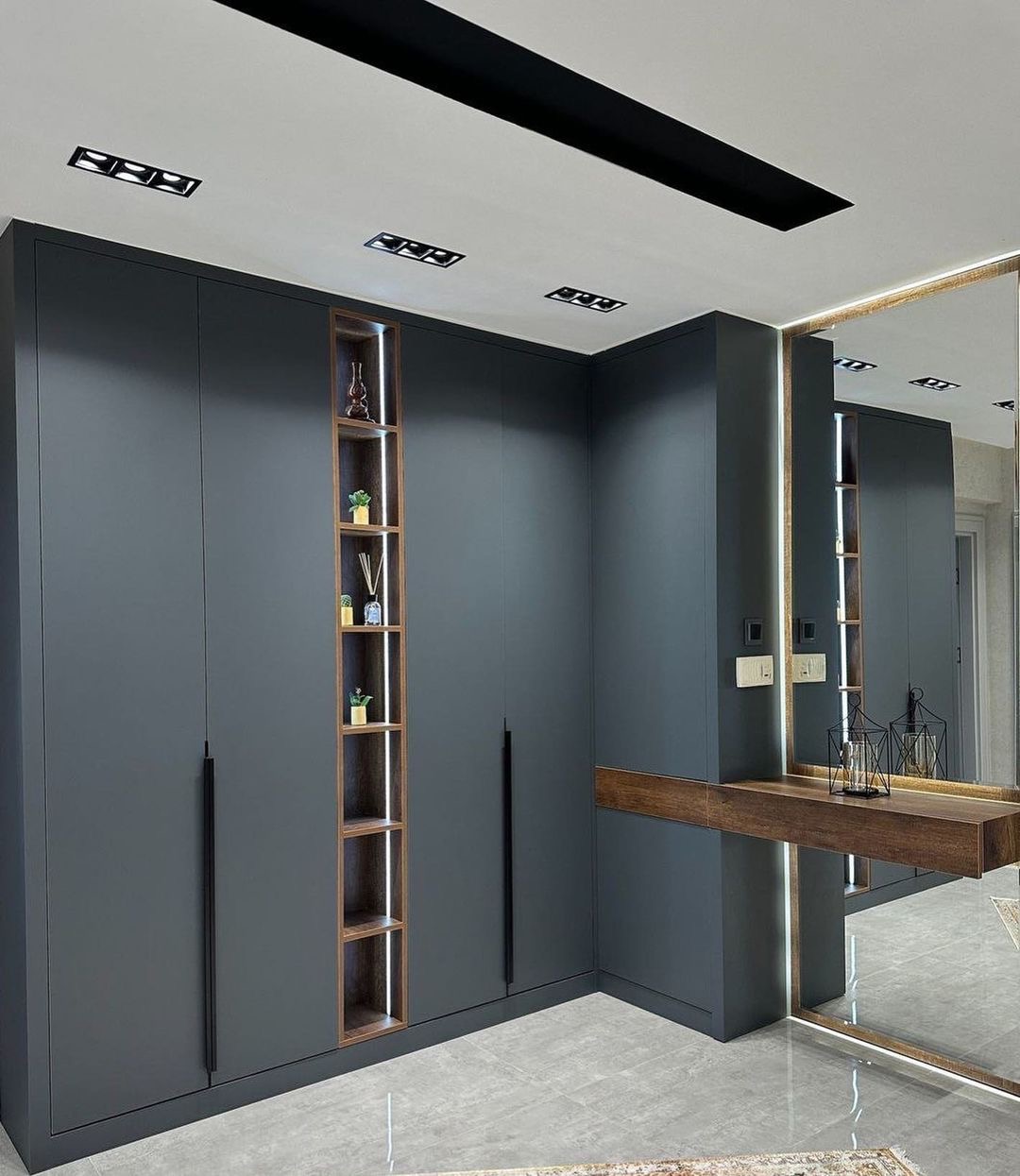 Nowoczesna, szara szafa wnękowa z podświetlanymi półkami, uzupełniona toaletką z lustrem z podświetleniem LED.