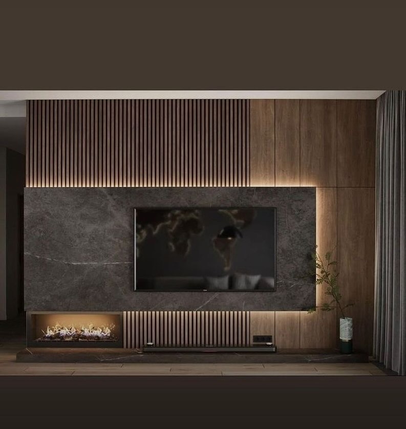 Nowoczesna ściana telewizyjna z marmurowym panelem, wbudowanym kominkiem elektrycznym i drewnianymi lamelami z podświetleniem LED, uzupełniona rośliną w dekoracyjnym wazonie.