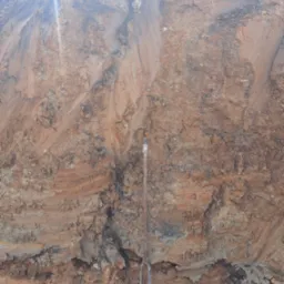 Przekrój warstw ziemi o różnej strukturze i kolorystyce z sondą geologiczną wbitą w grunt.