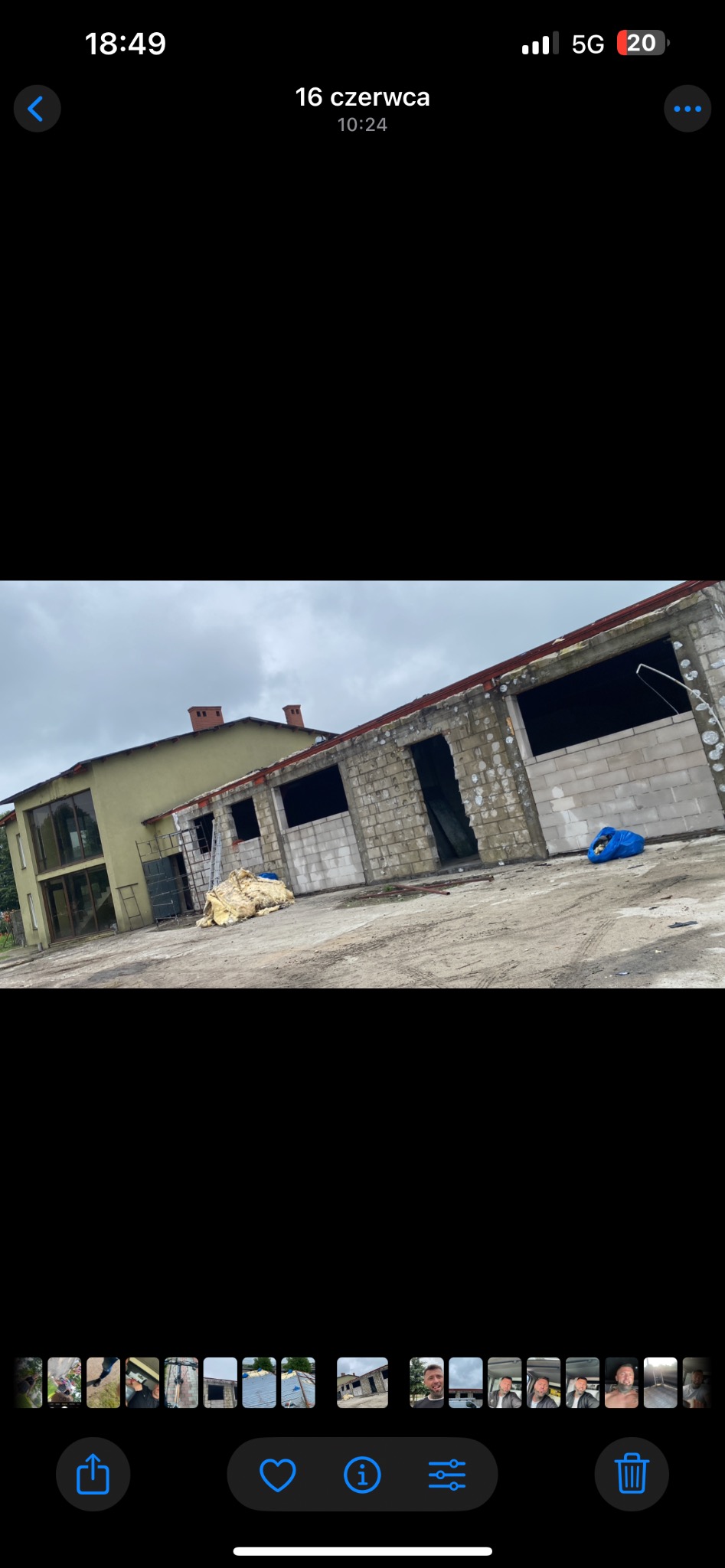 Budynek w trakcie prac dekarskich: widoczne mury z pustaków, częściowo zdjęty dach, drabina oparta o ścianę. Na ziemi leżą materiały izolacyjne.