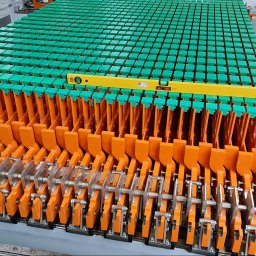 LEGAL & TECHNICAL SUPPORT CENTRE SPÓŁKA Z OGRANICZONĄ ODPOWIEDZIALNOŚCIĄ - Szczegółowe ujęcie formy do prefabrykatów betonowych z elementami pomalowanymi na pomarańczowo i zielono, sprawdzanej poziomicą, z widocznym fragmentem osoby w prawym górnym rogu.