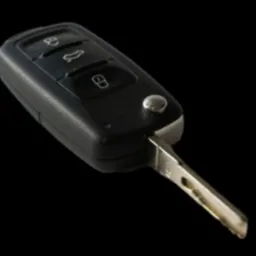 Kluczyk samochodowy z pilotem, trzy przyciski (otwieranie, bagażnik, zamykanie), metalowy grot, czarne tworzywo, czarne tło.