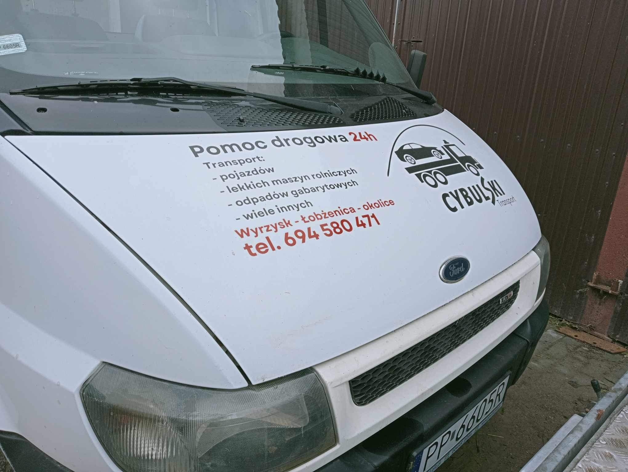 Biały samochód dostawczy z naklejonym logo firmy 'CYBULSKI Transport' oferującej pomoc drogową 24h, transport pojazdów, maszyn rolniczych, odpadów gabarytowych oraz inne usługi na terenie Wyrzyska...